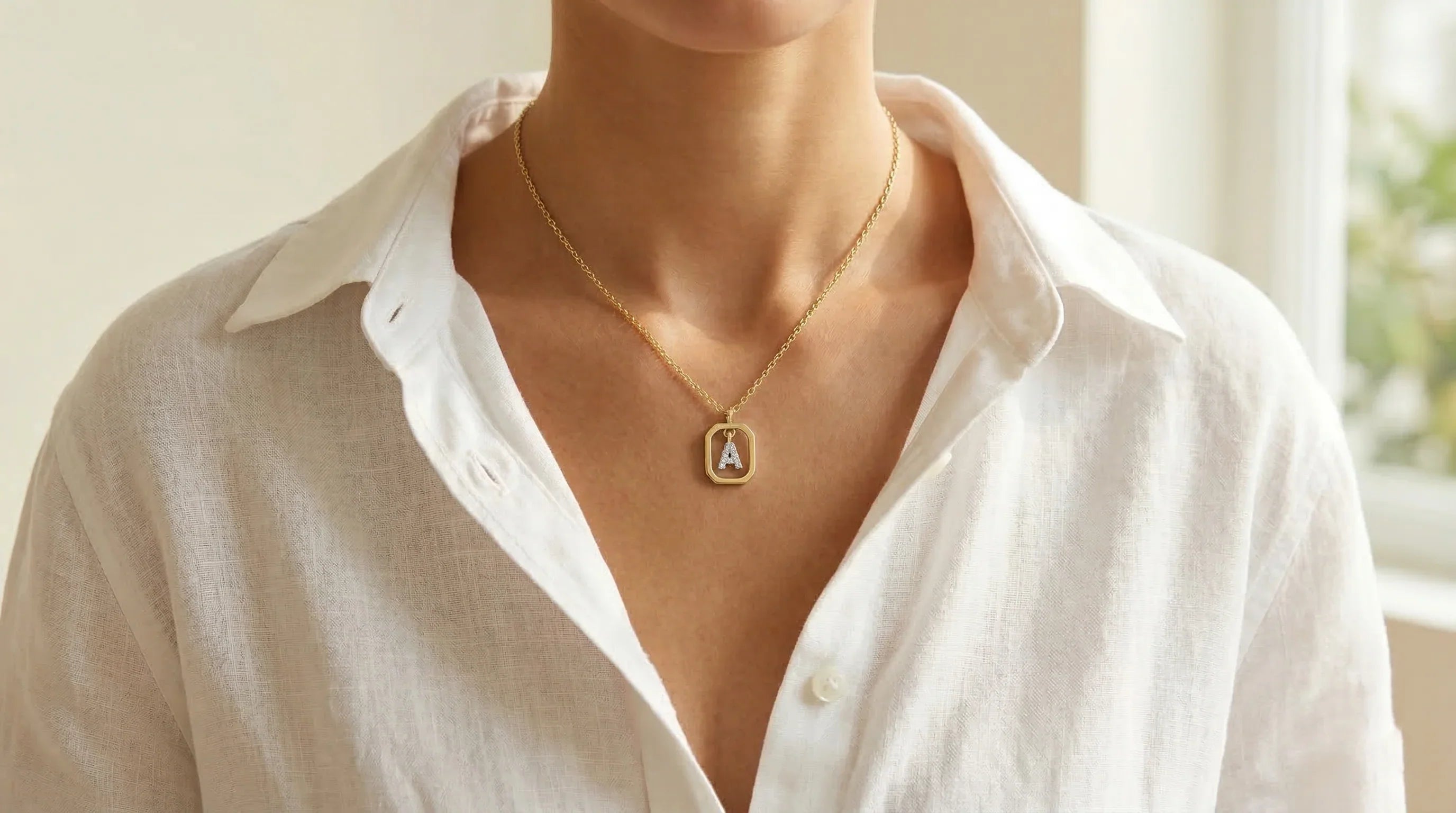 Woman wearing an everyday silver initial necklace styled with a crisp white linen shirt.