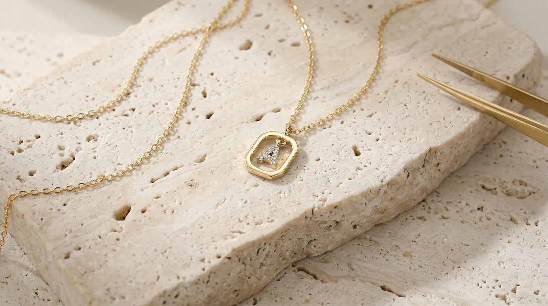 The Signature 925 sterling silver initial necklace resting on travertine stone, showcasing its delicate chain and tarnish-resistant pendant.
