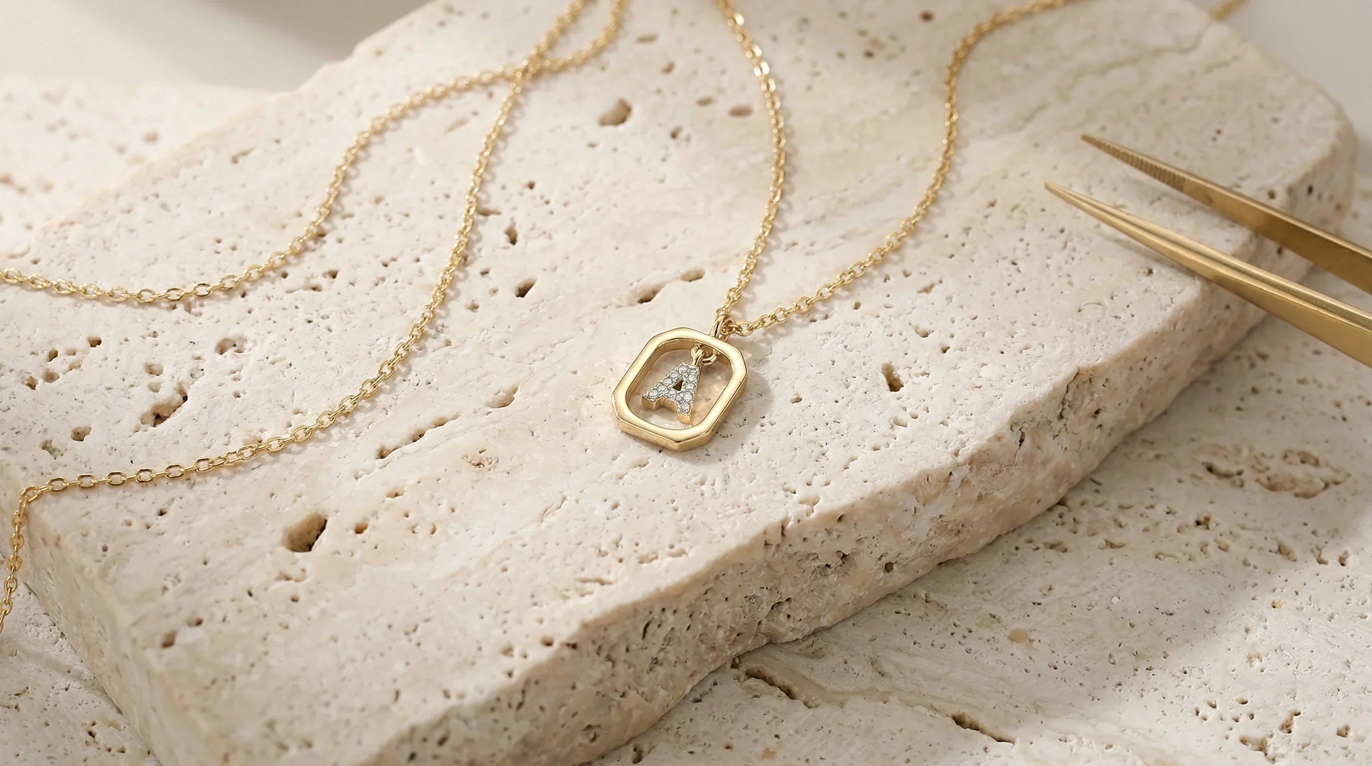 The Signature 925 sterling silver initial necklace resting on travertine stone, showcasing its delicate chain and tarnish-resistant pendant.