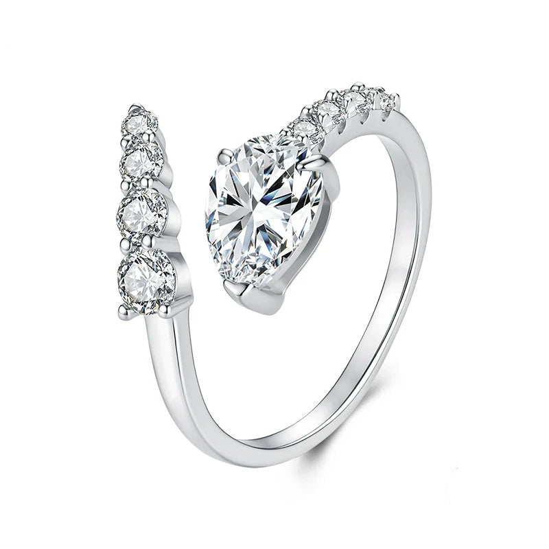 A silver-toned open ring with a large heart-shaped clear gemstone and smaller clear stones along the split band.