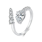 A silver-toned open ring with a large heart-shaped clear gemstone and smaller clear stones along the split band.