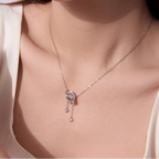 A close-up of a model wearing a delicate silver necklace with a rose-shaped pendant and dangling clear stones.