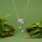 A silver-toned 925 sterling silver pendant necklace with a celestial ring design and dangling clear gemstones, set against a sage green background.