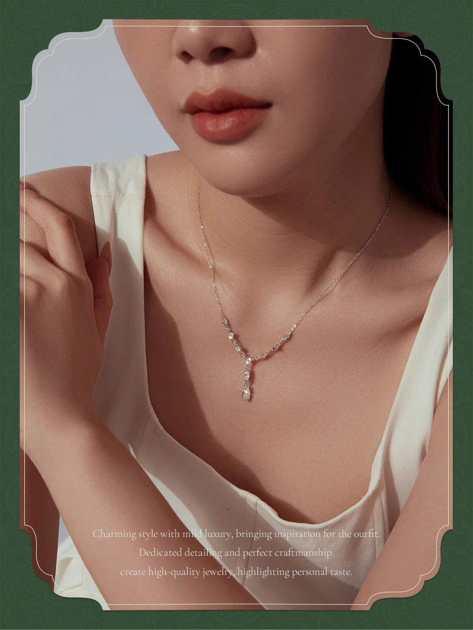 A close-up lifestyle shot of a model wearing a delicate silver Y-shaped necklace with small sparkling stones, styled with a cream-colored top against a dark green and beige graphic background.