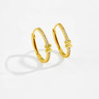 Gold hoop earrings with embedded stones on a light gray background