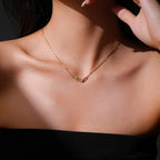 Gold necklace with a pendant on a person's neck against a dark background