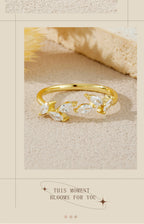 Gold ring with floral design on a textured beige surface