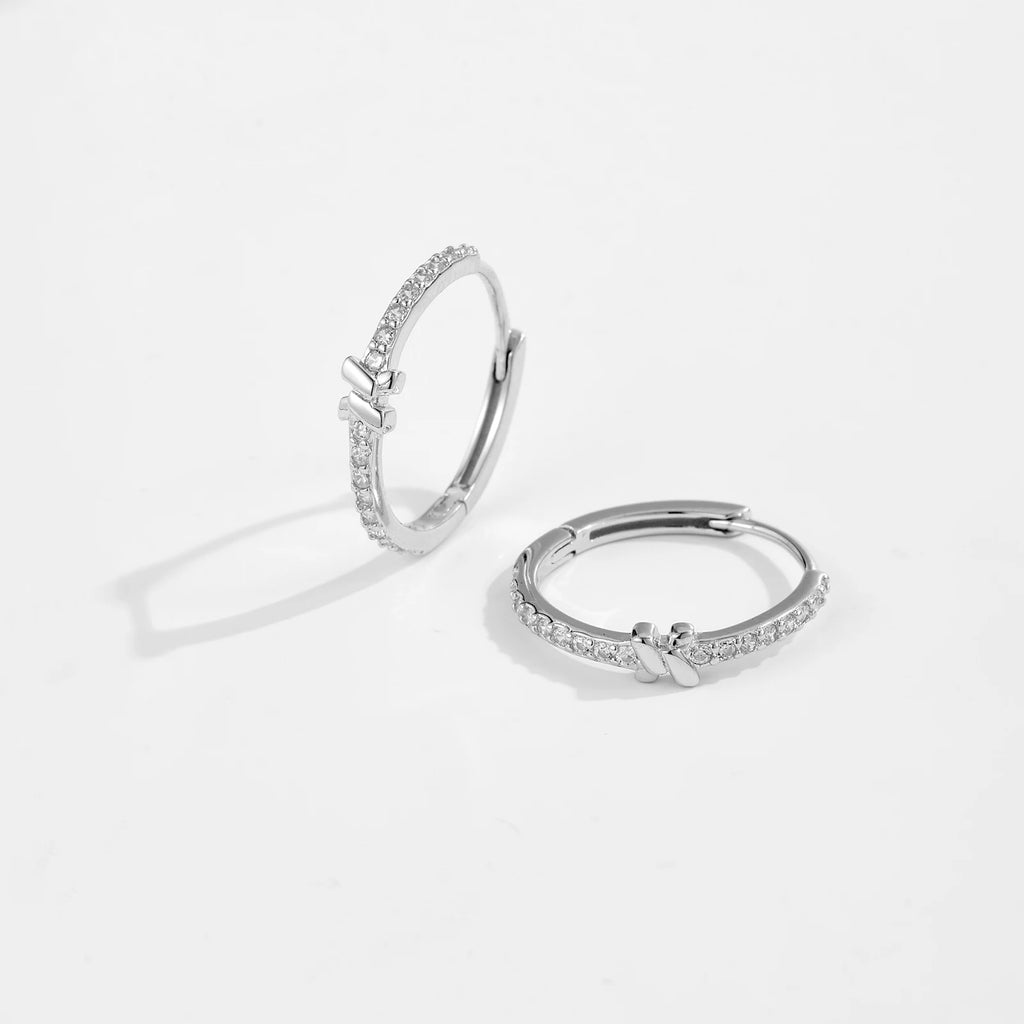Pair of silver hoop earrings with small diamonds on a light gray background