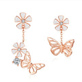 Rose gold butterfly and flower earrings with white stones on a white background