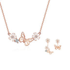 Rose gold butterfly and flower necklace with matching earrings on a white background