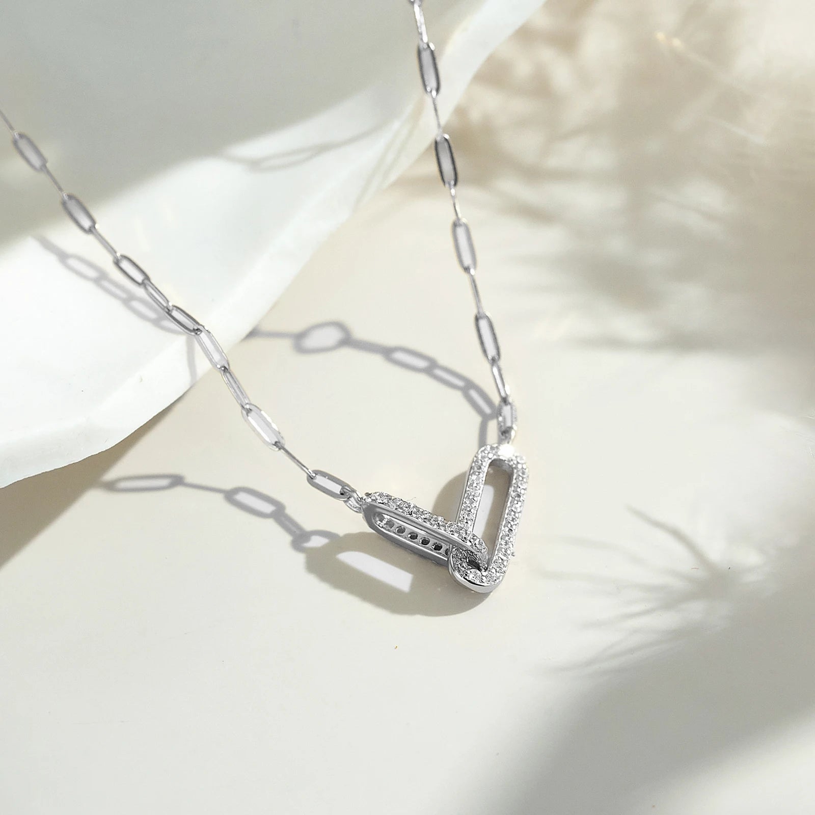 Silver necklace with a V-shaped pendant on a light background