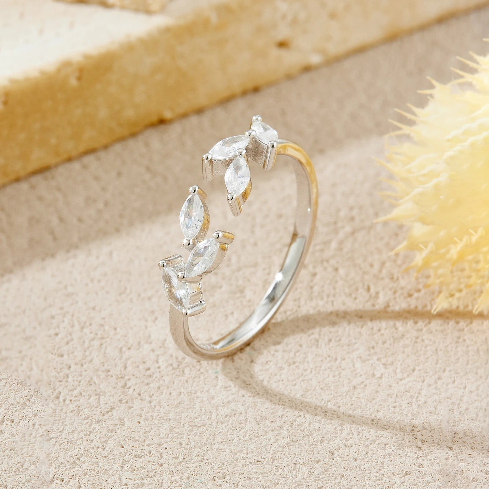 Silver ring with marquise-shaped stones on a sandy surface