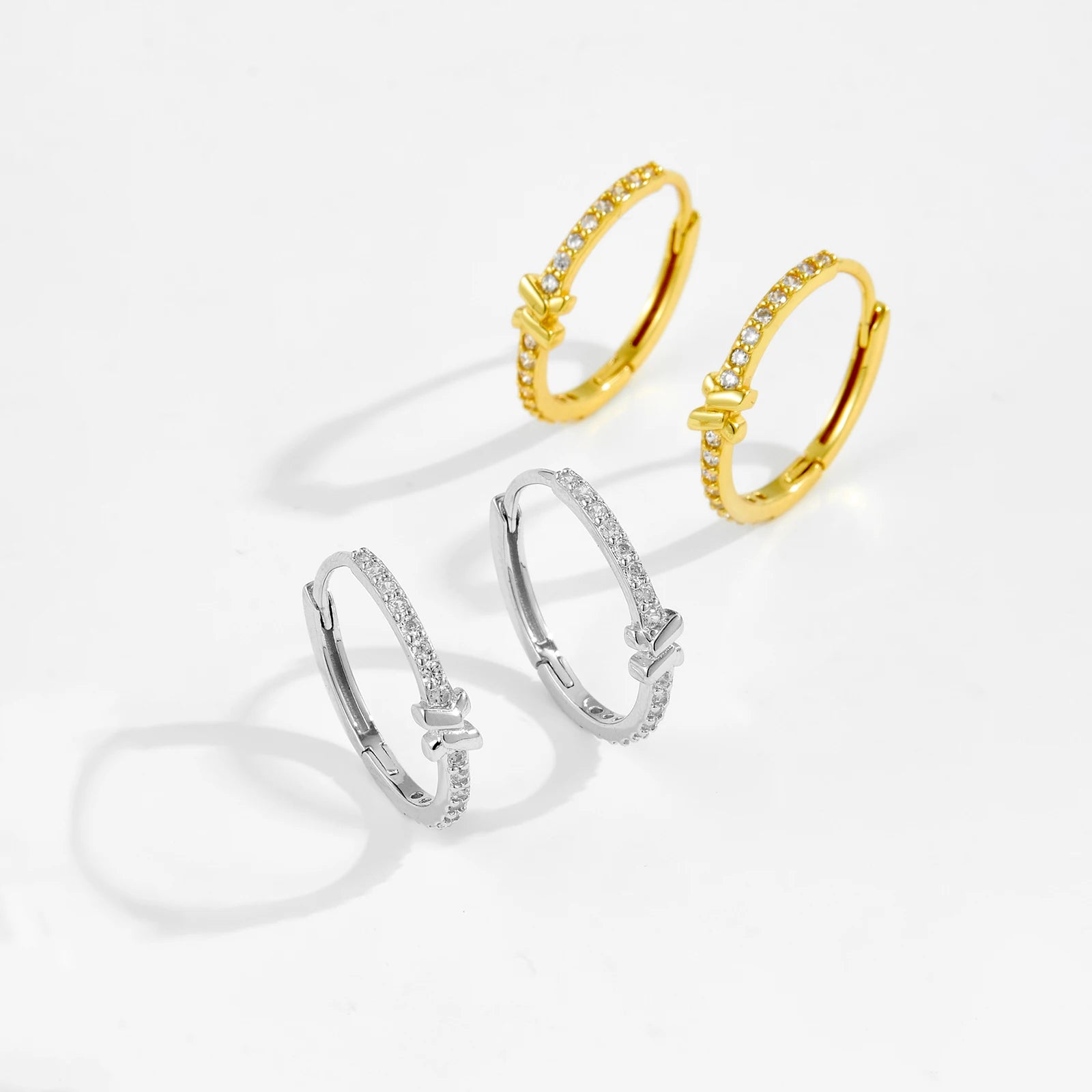 Three earrings in gold, silver, and gold on a white background