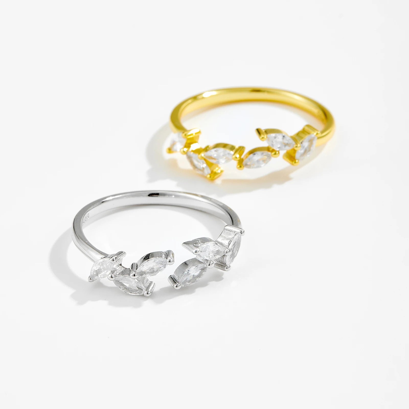 Two rings, one gold and one silver, with diamond-like stones on a white background
